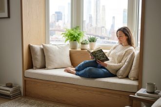 Femme lisant un livre dans un bow window lumineux et confortable